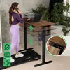 A woman is using a treadmill while working on a standing desk. Produktbild-Vorschau