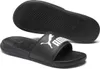 A pair of black Puma slide sandals is shown from a slightly elevated angle, with one sandal in the foreground and the sole of another sandal visible in the background. Anteprima dell’immagine prodotto