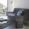 A modern living room scene with a sofa, floor lamp, coffee table, and a small trash can. Produktbild-Vorschau