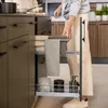A person is pulling out a kitchen cabinet drawer with towels and containers inside. Produktbild-Vorschau