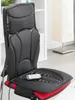 A black and red shiatsu massage seat mat is shown on a chair in a room with a white bookshelf and a floor lamp. Náhľad obrázku produktu
