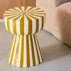 A striped side table next to a textured sofa. Produktbild-Vorschau