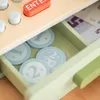 A close-up view of a toy cash register drawer filled with toy coins and some toy money. Produktbild-Vorschau