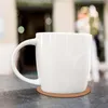 A white mug sits on a dark textured surface, with a blurred background. Produktbild-Vorschau