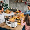 A family is gathered around a table, enjoying a meal with fried food. Produktbild-Vorschau