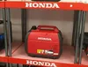 A red Honda generator is displayed on a shelf in a retail environment. Produktbild-Vorschau