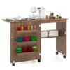 A sewing machine and supplies are neatly organized on a wooden sewing cabinet with shelves and wheels. Produktbild-Vorschau
