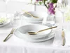 A table setting with white porcelain plates and gold cutlery, set for a meal. Produktbild-Vorschau