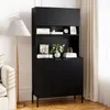 A black cabinet with shelves and doors, displayed in a room setting with a lamp and a sofa. The cabinet has decorative items on its shelves. Náhled obrázku produktu