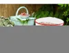 A light blue picnic basket with a small bowl of red berries sits on a table outdoors, next to a white bowl with a red rim filled with food. Produktbild-Vorschau