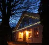 A house decorated with string lights at dusk. Produktbild-Vorschau