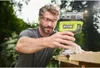 A man is using a Ryobi router on a piece of wood outdoors. Anteprima dell’immagine prodotto