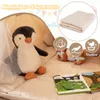 A plush penguin toy sits inside a play tent with a folded mat and children's books visible. Podgląd zdjęcia produktu