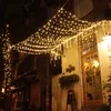 A building facade decorated with strings of warm white fairy lights at night. Produktbild-Vorschau