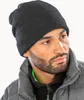 A man wearing a black beanie and a grey puffer jacket. Anteprima dell’immagine prodotto