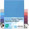 A stack of folded fitted sheets in various colors, with the main product in a bright blue color prominently displayed. The image also includes cotton bolls and branding. Produktbild-Vorschau