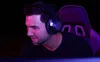 A man wearing headphones and a gaming chair in the background. Produktbild-Vorschau