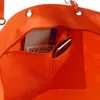 Close-up view of the inside of an orange tote bag, showing a zippered pocket with a book and a smartphone inside. Podgląd zdjęcia produktu