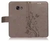 A close-up view of a brown flip phone case with a floral and butterfly embossed design. Produktbild-Vorschau