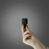A hand holding a black power adapter against a gray background. Podgląd zdjęcia produktu