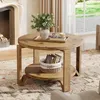 A round wooden coffee table with two shelves, decorated with a vase of flowers and books, in a living room setting. Produktbild-Vorschau