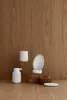 A white ceramic soap dispenser and other bathroom accessories are arranged on a wooden surface against a wooden wall. Produktbild-Vorschau
