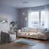 A modern living room with a sofa, armchair, coffee table, and a large window overlooking a snowy cityscape. Produktbild-Vorschau