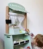 A child playing with a wooden market stall toy. Produktbild-Vorschau