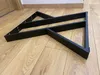 A black metal table leg frame is lying on a wooden floor. Anteprima dell’immagine prodotto