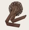 A single brown satin bonnet with long ties is laid out on a light gray background. Podgląd zdjęcia produktu