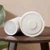 A white smart thermostat and a white smart gateway are placed on a wooden table. Produktbild-Vorschau