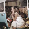 A young woman sits in a vehicle filled with teddy bears, holding earbuds. Produktbild-Vorschau