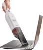 A hand is holding a white handheld vacuum cleaner and using it to clean a laptop keyboard. Produktbild-Vorschau