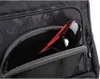 A close-up view of a black rucksack with a camouflage pattern, showing a zippered pocket with red-framed sunglasses and a dark object inside. Produktbild-Vorschau
