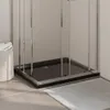 Close-up of a black rectangular shower tray with chrome-effect framing, set against a tiled wall and a light gray floor mat. Produktbild-Vorschau