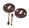Two brown keyhole escutcheons and two brass screws with brown plastic caps are arranged on a white background. Anteprima dell’immagine prodotto