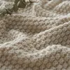 A close-up view of a textured, knitted blanket. Produktbild-Vorschau