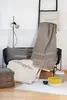 A collection of home decor items including pillows, a blanket, and decorative baskets arranged on a rug in a room. Produktbild-Vorschau