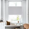 A bright room with a large window covered by a light gray pleated blind. There are decorative pillows and a teapot on the windowsill. Produktbild-Vorschau