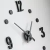 A close-up view of a modern, minimalist wall clock with black numbers and hands on a white background. Náhled obrázku produktu