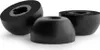 Three black earbud tips are arranged on a white background. Two are shown in cross-section, revealing their foam interior and a central channel. The third is shown whole. Produktbild-Vorschau