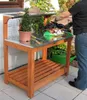 A person is using a wooden potting table with a metal top outdoors. Anteprima dell’immagine prodotto