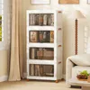 A stack of four white storage boxes with clear doors and orange handles, filled with books and decorative items, placed in a living room setting next to a window with beige curtains and a floor lamp. Podgląd zdjęcia produktu