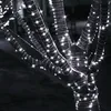 Close-up of tree branches wrapped in white LED string lights at night. Náhled obrázku produktu