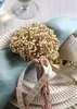 A table setting with a plate, napkin, and a decorative dried flower arrangement tied with a ribbon. Produktbild-Vorschau