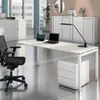 A modern office desk setup with a white desk, black office chair, and filing cabinet. Produktbild-Vorschau