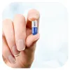 A hand is holding a single capsule. Produktbild-Vorschau