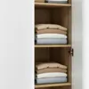 A close-up view of shelves inside a wardrobe, showing neatly folded stacks of bedding in various neutral colors. Anteprima dell’immagine prodotto