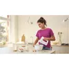 A woman is mixing ingredients in a bowl with a hand mixer in a kitchen. Produktbild-Vorschau