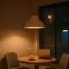 A pendant lamp illuminates a table with a laptop and a cup of coffee, next to a window showing a street light reflection. Produktbild-Vorschau
